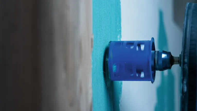 Scie cloche en train de découper une plaque de plâtre sur un mur intérieur peint.